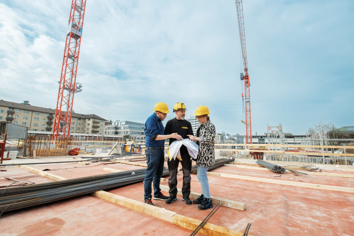 Drei Mitarbeiter beraten sich auf einer Baustelle